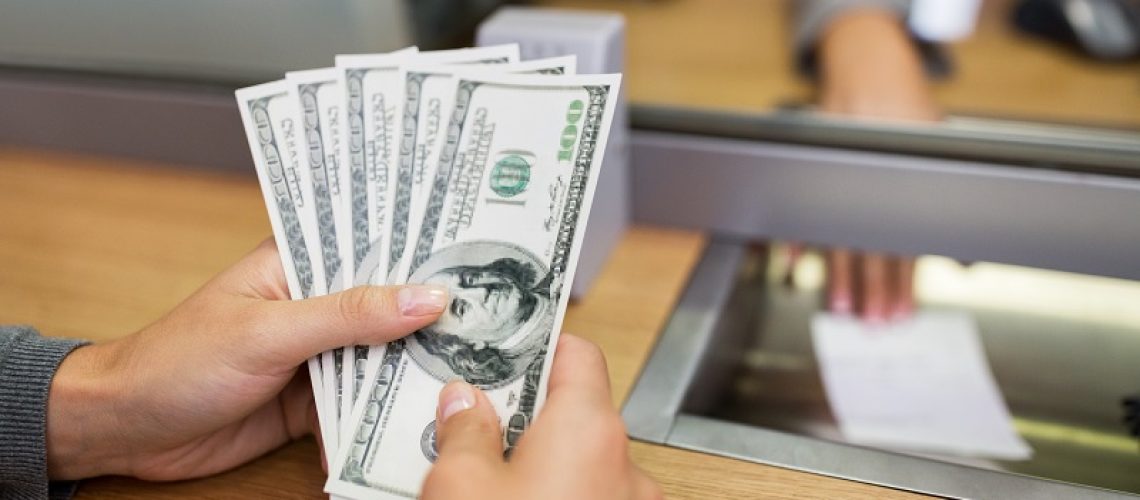 people, withdrawal, saving and finance concept - customer hands with cash money at bank office or currency exchanger